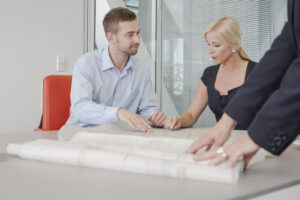 Client discussing blueprints with Contractor in an office