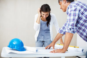 Young woman discussing home renovations with contractor and viewing blueprint